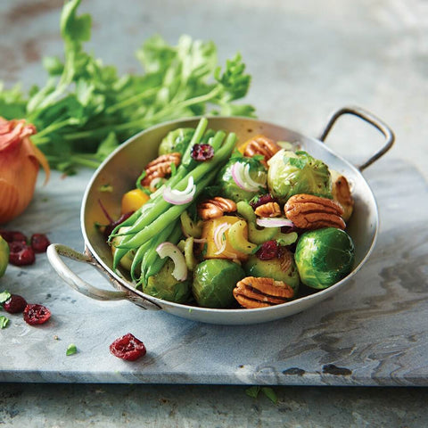 Brussels Sprouts cooked in a round dish with green beans, tomatoes and onions, front view.