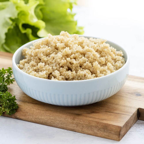 Golden Quinoa in a bowl with salad leaves, front view.