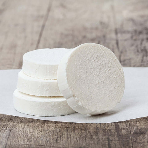 4 Goat Cheese Slices arranged on a sheet of baking paper on a table, seen from the front.