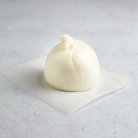 Italian Frozen Burratta laid on baking paper on marble, front view.