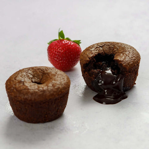 2 Lava Cake on marble, one open with a strawberry next to it, front view.