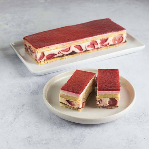 A large Strawberry Strip Cake placed in a tray and two small pieces of Strawberry Strip Cake placed in a round plate, seen from the front. 