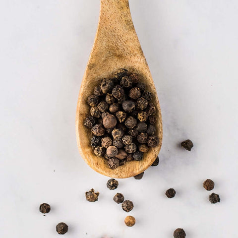 Wooden spoon containing Black Penja Pepper, seen from above.