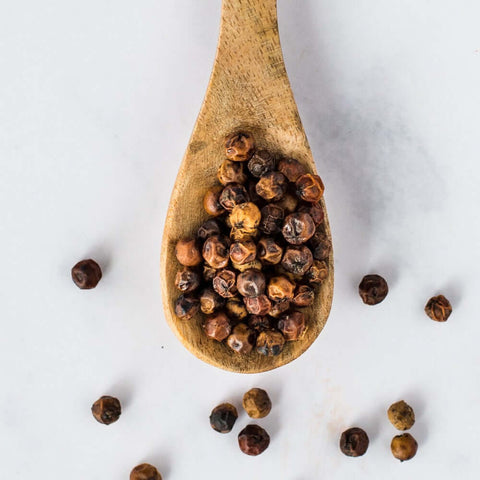 Wooden spoon containing Red Kampot Pepper, seen from above.