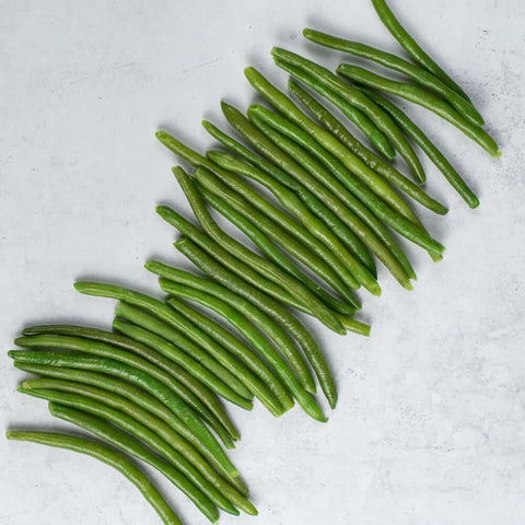 Extra Fine Green Beans scattered on marble, seen from above.