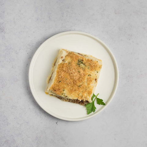 Hachis Parmentier (Beef Shepherd's Pie) cooked in a round plate with a coriander leaf, seen from above.