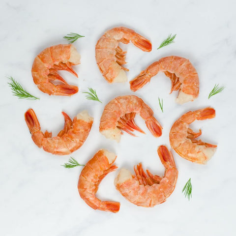Assortment of 8 Ez-Peel Shrimp arranged on marble with some leaves of chives, seen from above.