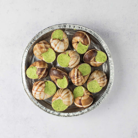 Assortments of 12 Escargots in Parsley-Garlic Butter arranged in their aluminum dishes, seen from above.