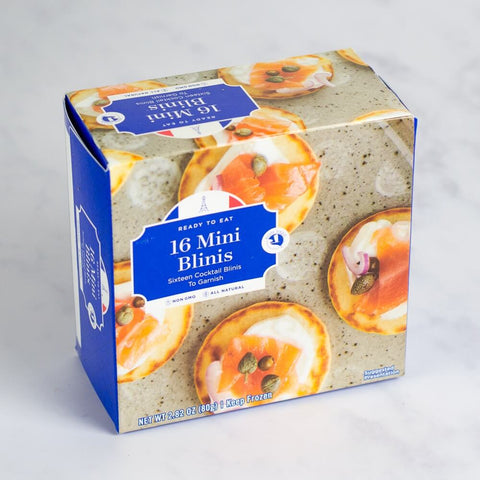 Assortments of 16 Mini Blinis in their cardboard packaging, placed on marble, front view.