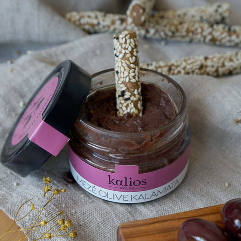 Smoked Eggplant Meze from Kalios, in an open glass jar with a breadstick in it, placed on a wooden board, front view.