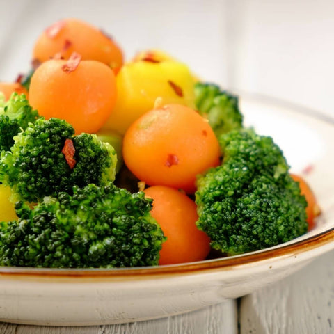 Tray filled with assorted Parisian carrots and other vegetables placed on marble, front view.