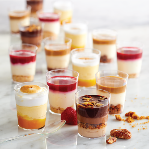 Assorted dessert shots: cheesecake with raspberries, mascarpone with speculoos crumbs, dark chocolate mousse with praline, and passion fruit meringue