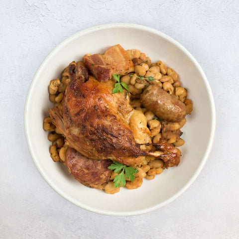 Cassoulet cooked in a round dish on marble, seen from above.