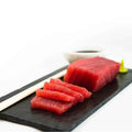 Sliced Yellowfin Saku Wild Tuna placed on a slate, side view.