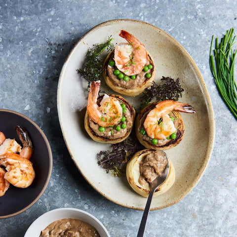 Artichoke bottoms cooked with shrimps and Extra Fine French Peas, put in a plate, seen from above.