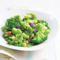 Assorted Peeled Fava Beans and other green vegetables on a round plate, seen from the front. 