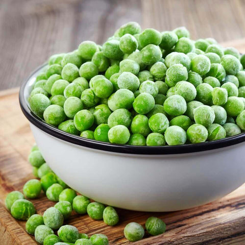 Bowl filled with Extra Fine French Peas, placed on a wooden tray, seen from the front.