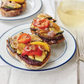 Assorted Mixed Grilled Vegetables arranged on bread, and placed in a round plate, seen from the front. 