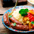 Lamb Merguez Sausage cooked in a plate with semolina and vegetables, front view.