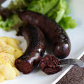 Blood Sausage (Boudin Noir) cooked on a plate with potatoes and salad, front view.