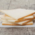 5 slices of raclette cheese stacked on baking paper, placed on a table, front view.