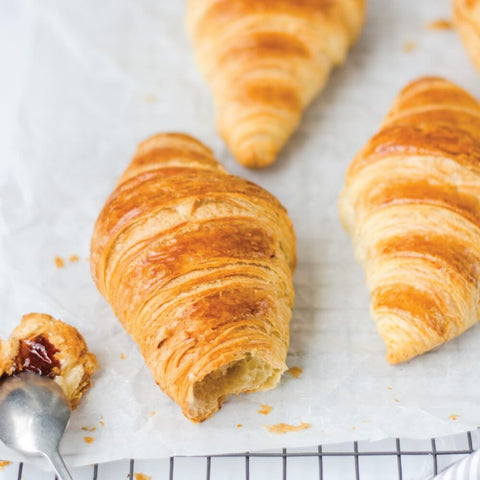 3 French Butter Croissants placed on a grid with baking paper, front view.