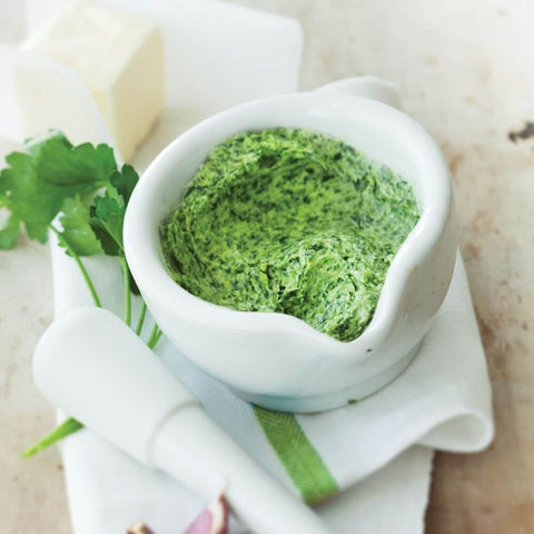 Garlic & Herbs Butter Roll cream and put in a small jar with some basil leaves, seen from above.