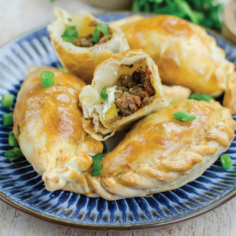 Assorted Empanada Dough cooked with ground meat and vegetables, placed in a round plate, seen from the front.