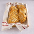 Assortment of 6 apple turnovers placed on a cloth in a basket, seen from above. 