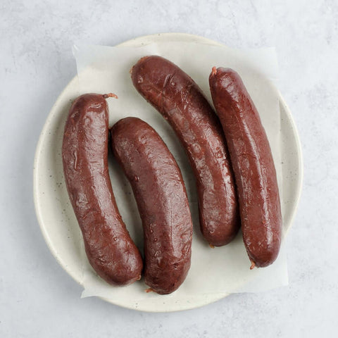 Blood Sausage (Boudin Noir) laid out in a round plate, on baking paper, seen from above.