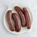 1 pack of 4 pcs Boudin Noir in a round plate on marble, seen from above.