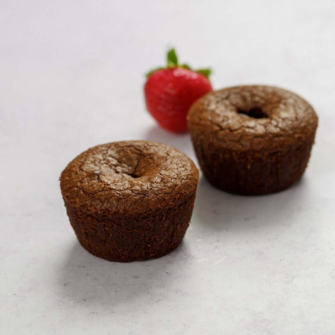 2 Chocolate Lava Cake on marble with a strawberry next to it, front view.