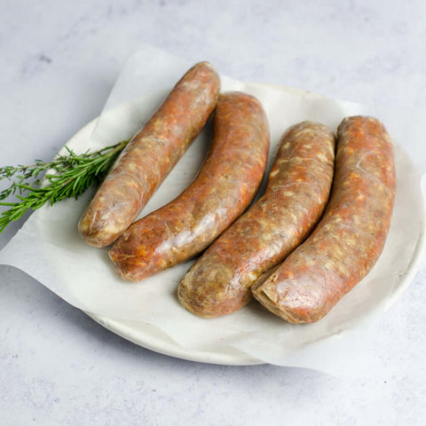 Chorizo Spanish Style Sausage laid out in a round plate, on baking paper, with a branch of thyme, seen from above.