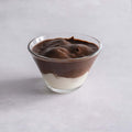 Coppa Profiterol served in a glass bowl on marble, front view.