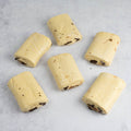 6 Chocolate Croissants not yet baked, set on marble, seen from above.