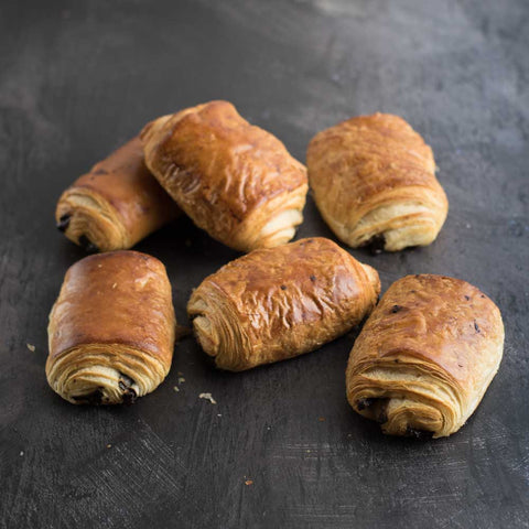 6 Chocolate Croissants baked, arranged on a table, seen from above.