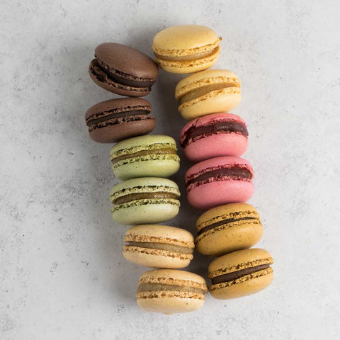 Assortment of 12 Classic French Macarons on marble, seen from above.