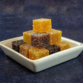 Assortment of Fruit Paste Squares of the brand Ile De Ré Chocolats, arranged in a pyramid in a ramekin, side view. 