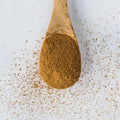 Wooden spoon containing Ground Ceylon Cinnamon spices, seen from above.