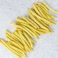 Assortment of Very Fine Yellow Wax Beans arranged on marble, seen from above.