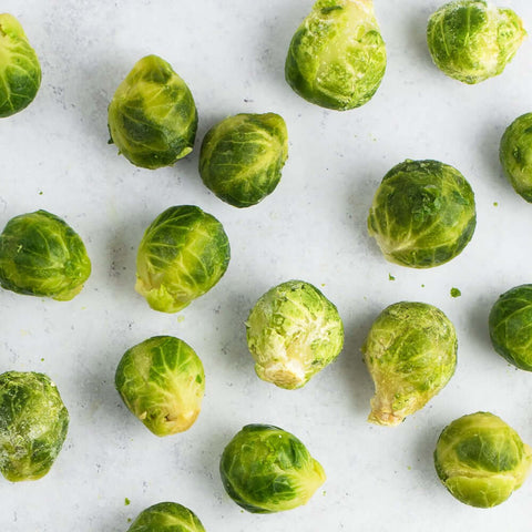 Assortments of Brussels Sprouts scattered on marble, seen from above. 