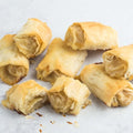 Assortment of 8 Brie & Pear Fillo Rolls arranged on marble, front view. 