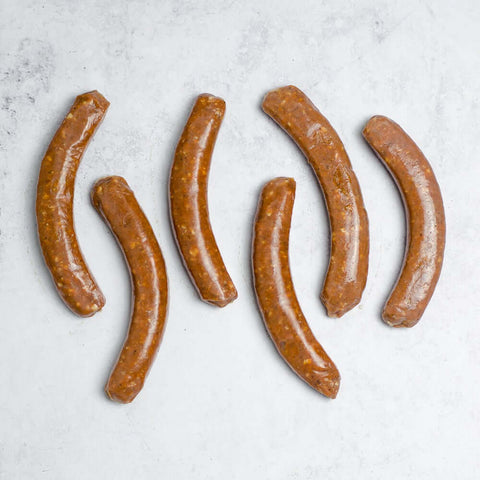 6 Lamb Merguez Sausage arranged on marble, seen from above.