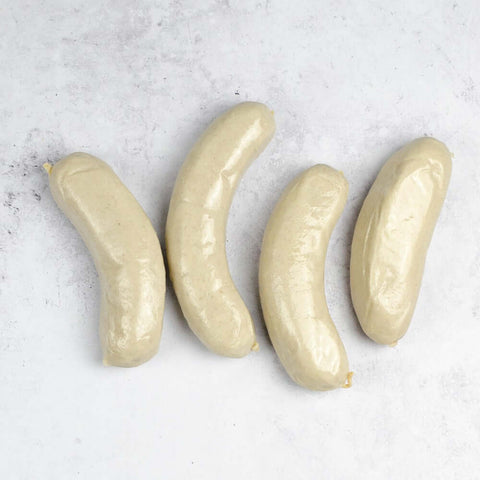Assortment of four White Pudding Sausage (Boudin Blanc) arranged on marble, seen from above.
