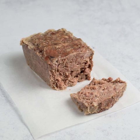Pâté de Campagne cut in two, laid on a baking sheet on marble, side view. 