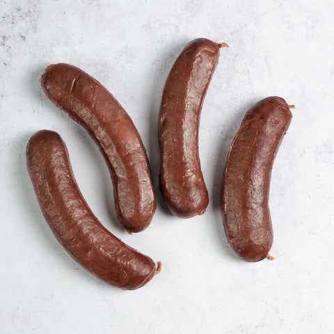 Assortment of four Blood Sausage (Boudin Noir) arranged on marble, seen from above.
