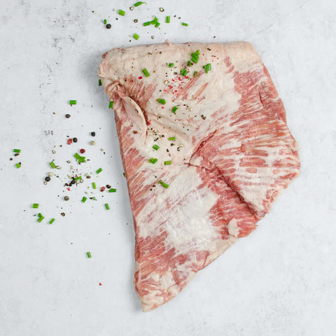 Ibérico Pork Secreto arranged on marble with chives, seen from above.