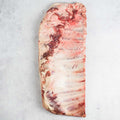 Ibérico Pork Spare Ribs placed skin side down on marble, seen from above. 