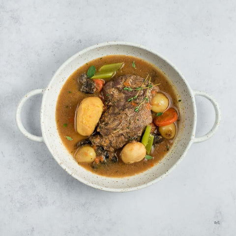 Coq au Vin cooked in a round dish on marble, seen from above.