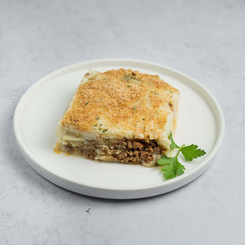 Hachis Parmentier (Beef Shepherd's Pie) cooked in a round plate with a coriander leaf, seen from the front.